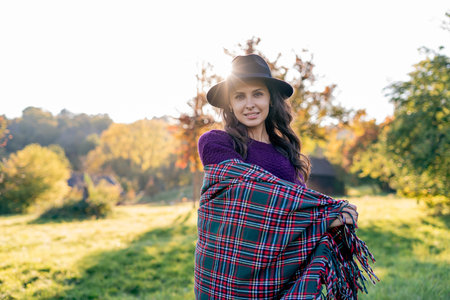 Autumn portrait of a young woman outdoors with a warm cozy blanket.の写真素材