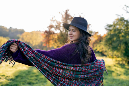 Autumn portrait of a young woman outdoors with a warm cozy blanket.