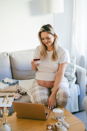 Young pregnant woman shopping online, paying with a bank card.の写真素材