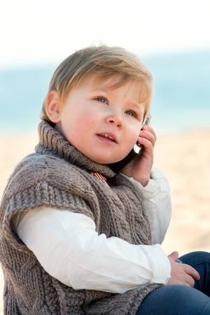 Portrait of cute little girl on beach talking on mobile phone の写真素材