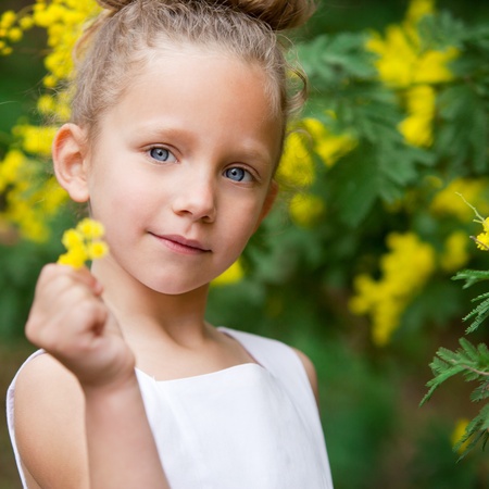 Close up portrait  of cute little girl showing yellow flower outdoors の写真素材