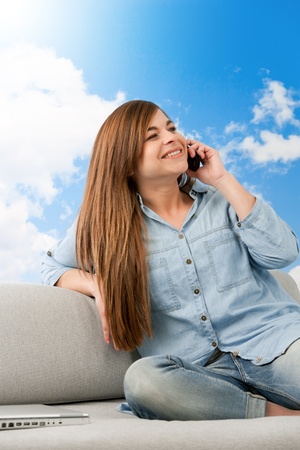 Portrait of brunette on couch talking on cellphone の写真素材