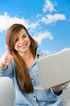 Close up portrait of cute girl showing thumbs up with laptop outdoors の写真素材