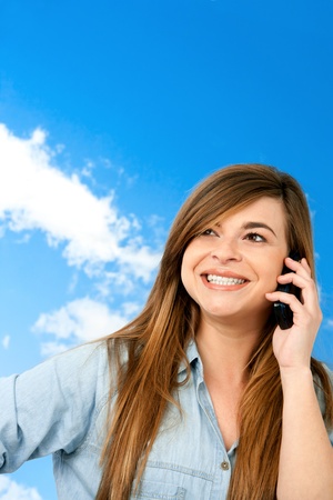 Close up portrait of cute smiling girl talking on cellphone outdoors の写真素材