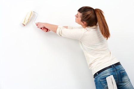 Portrait of cute female painter painting the wall の写真素材