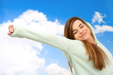 Young woman stretching arms outdoors on blue sky の写真素材