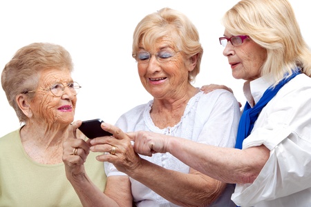 Close up portrait of three happy elderly women with cellphone Isolated on white の写真素材