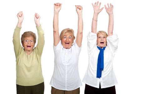 Portrait of three friendly senior women raising hands Isolated on white の写真素材