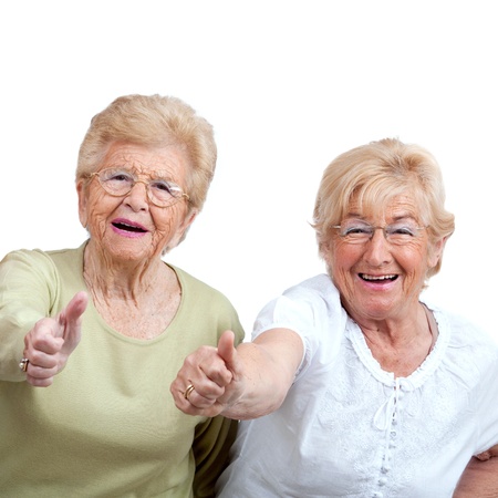 Close up portrait of two friendly senior women showing thumbs up Isolated on white の写真素材