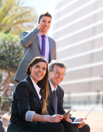 Business team working outdoors with digital tablet and laptop.の写真素材