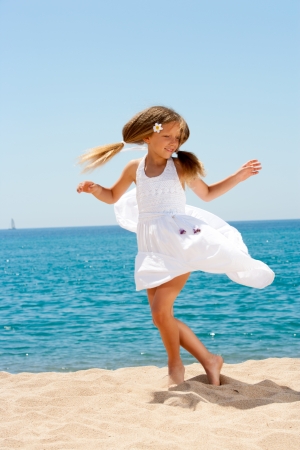 Cute girl in white dress dancing  on sunny beach の写真素材