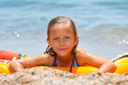 Cute girl having fun on air mattress on beach の写真素材