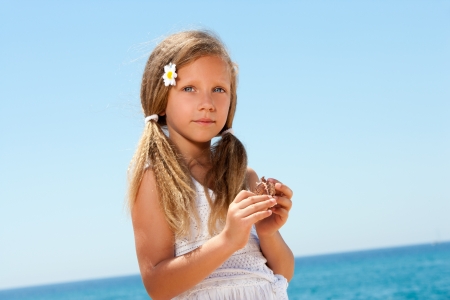 Portrait of sweet girl in white dress holding a shell の写真素材