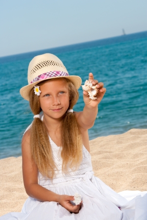 Close up portrait of sweet girl on beach showing shell の写真素材