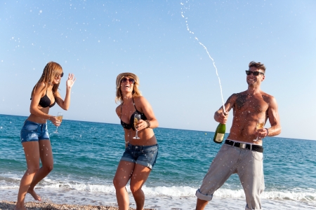 Friends having fun with champagne at celebration on beach,の写真素材