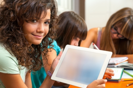 Portrait of young student at desk showing digital tablet with blank copy space の写真素材
