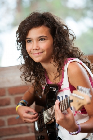 Close up portrait of cute girl playing guitar indoors の写真素材