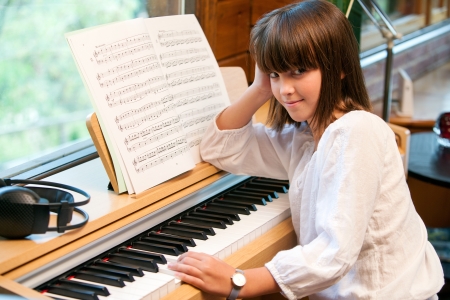 Close up portrait of little girl sitting at piano.の写真素材
