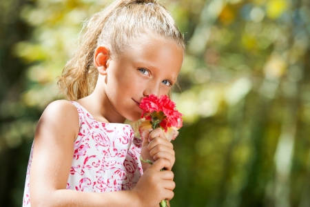 Close up portrait of blue eyed girl smelling flower outdoors.の写真素材