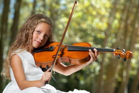 Close up portrait of young cute violinist playing in the woods.の写真素材