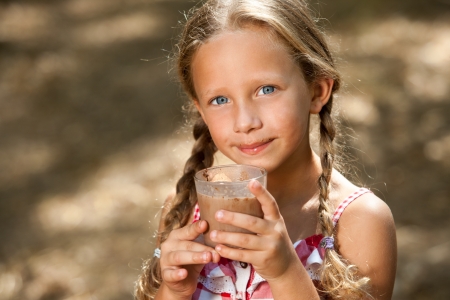 Close up portrait of cute girl drinking milk chocolate outdoors.の写真素材