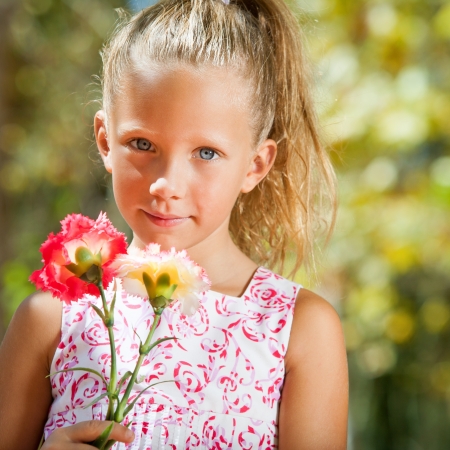 Close up portrait of cute girl holding flowers in garden.の写真素材