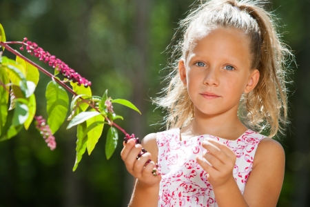 Close up portrait of cute girl outdoors picking wild berries.の写真素材
