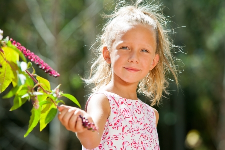 Close up portrait of cute girl picking wild berries in forest.の写真素材