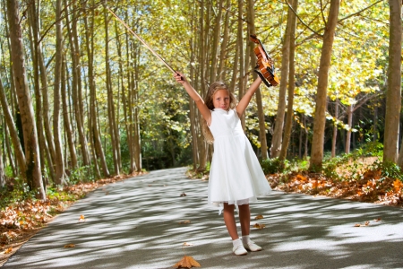 Full length portrait of young violinist raising arms in the woods.の写真素材