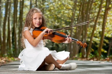 Portrait of young girl playing violin in the forest.の写真素材