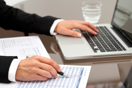 Close up of female hands reviewing accounting documents on table.の写真素材