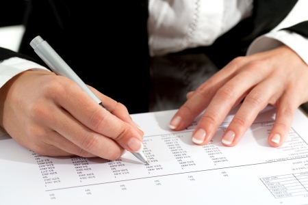 Close up of female hands with pen reviewing accounting document.の写真素材