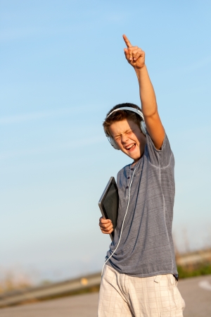 Cute boy feeling free with headphones and digital tablet outdoors の写真素材