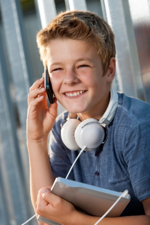 Close up portrait of smiling boy talking on smart phone outdoors の写真素材