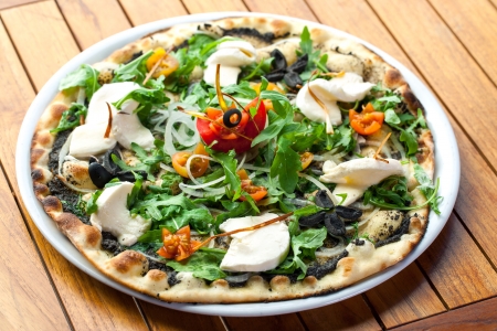 Close up of black olive and rucola pizza with fresh mozzarella cheese.の写真素材
