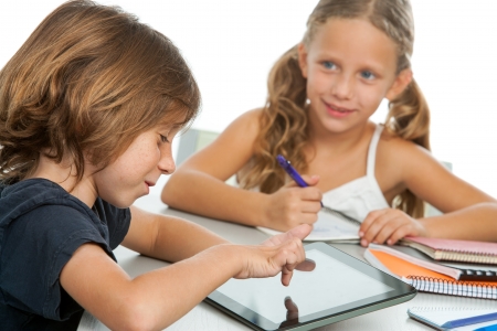 Portrait of two small kids doing homework on digital tablet.Isolatedの写真素材