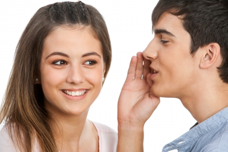 Close up of boy whispering to cute girl.Isolated on white.の写真素材
