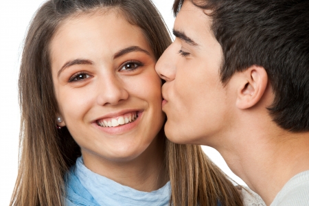 Close up portrait of boyfriend kissing girlfriend on cheek.Isolated on white.の写真素材