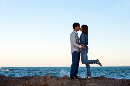 Romantic couple kissing on rocks at seaside.の写真素材