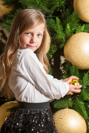 Portrait of cute little girl at home in front of christmas tree の写真素材