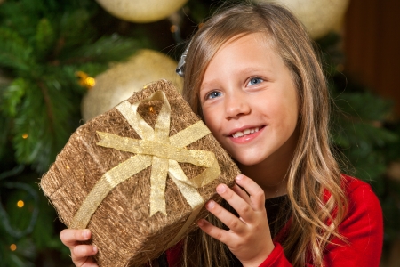 Close up portrait of cute girl holding present at christmas tree の写真素材