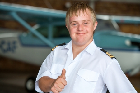 Portrait of young handicapped pilot showing thumbs up in hangar.の写真素材
