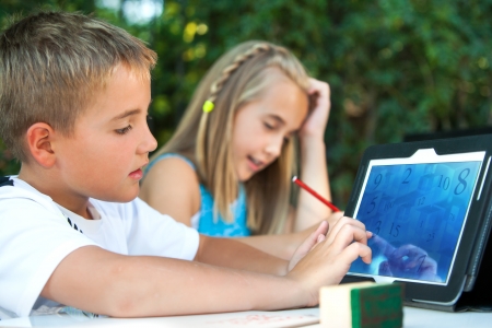 Cute boy student touching tablet screen outdoors.の写真素材