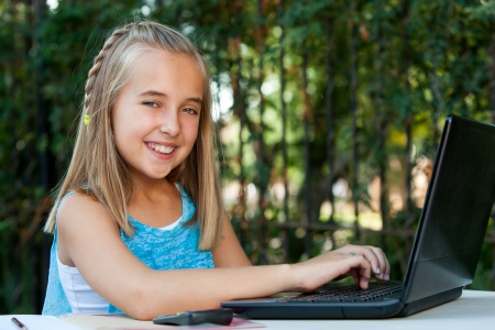 Portrait of young girl student doing schoolwork on laptop outdoors.の写真素材