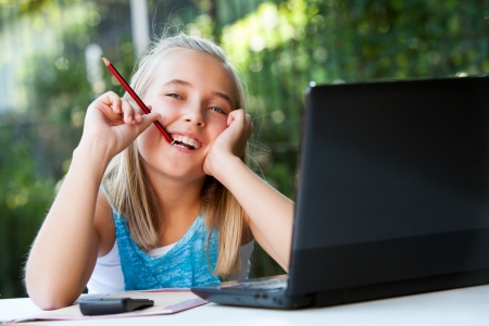 Portrait of cute girl with wondering expression doing schoolwork. の写真素材