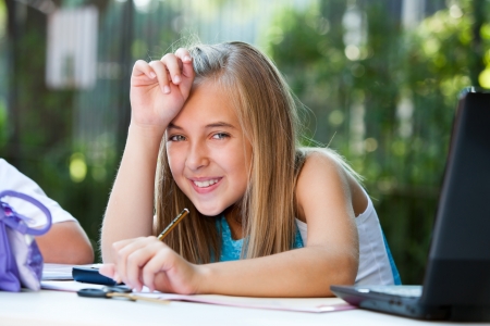 Close up portrait of cute girl student at desk in garden.の写真素材