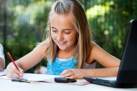 Young girl student doing homework with pencil outdoors.の写真素材