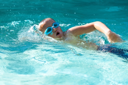 Small boy practicing in open air swimming pool.