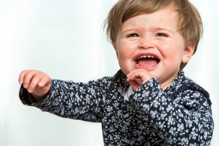 Portrait of little girl crying with arms raised.の写真素材