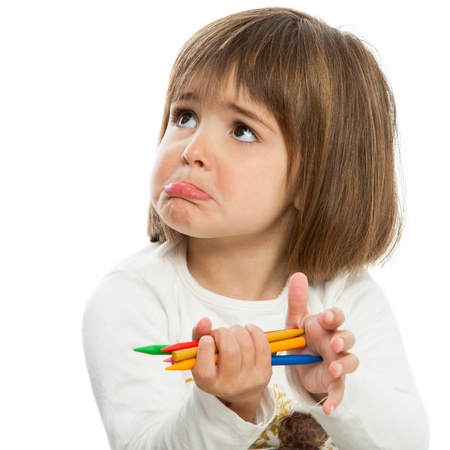 Unhappy little girl holding wax crayons.Isolated.の写真素材